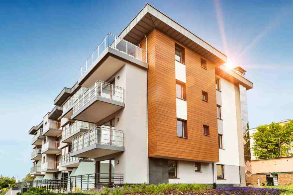 Modern apartment building with wood and gray facade under sunlight.